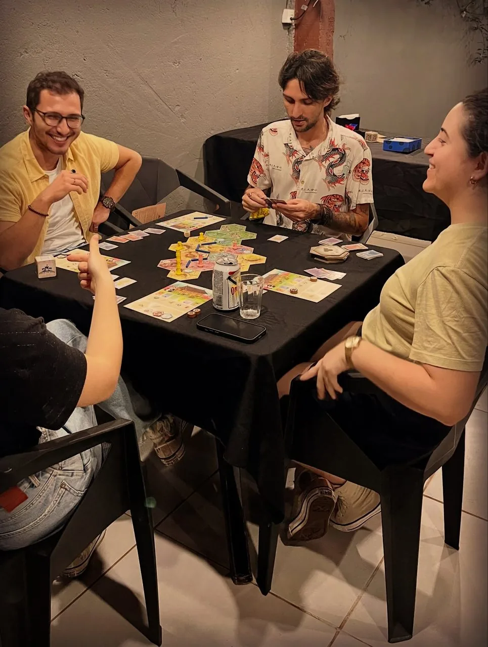 Amigos sorrindo durante uma partida de jogo de tabuleiro na mesa do salão